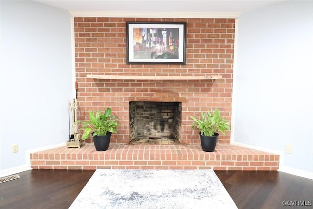 details with visible vents, baseboards, wood finished floors, and a fireplace