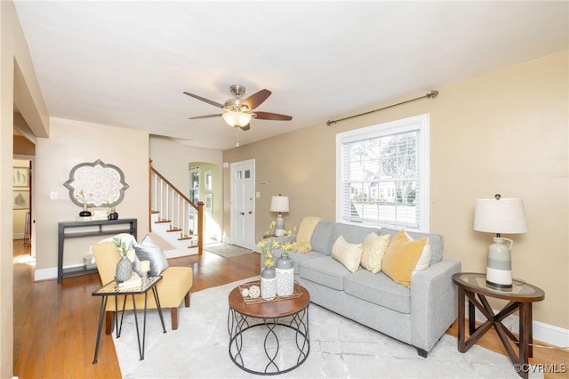 living area with ceiling fan, stairs, baseboards, and wood finished floors