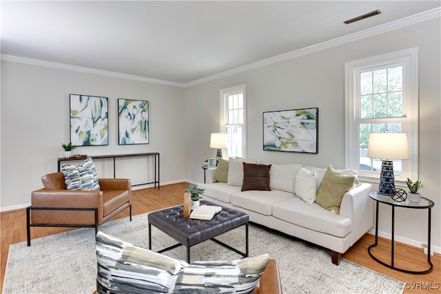 living area featuring visible vents, a healthy amount of sunlight, wood finished floors, and crown molding