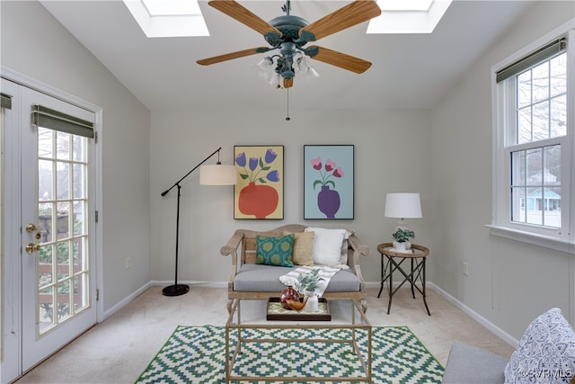 sitting room with vaulted ceiling with skylight, carpet flooring, a ceiling fan, and baseboards