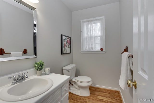 bathroom featuring toilet, vanity, baseboards, and wood finished floors