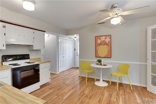 kitchen with light wood finished floors, ceiling fan, white cabinets, under cabinet range hood, and range with electric stovetop