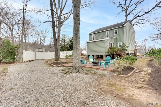 back of property featuring a fire pit, a wooden deck, and fence