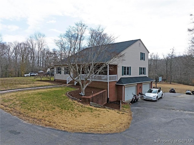 view of front of house featuring a front yard, stairway, driveway, an attached garage, and brick siding