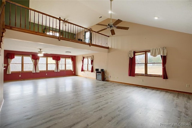 unfurnished living room featuring ceiling fan, baseboards, high vaulted ceiling, and wood finished floors