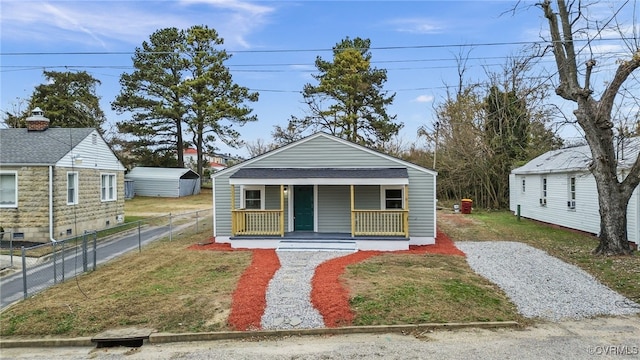 bungalow with covered porch, a front lawn, and fence