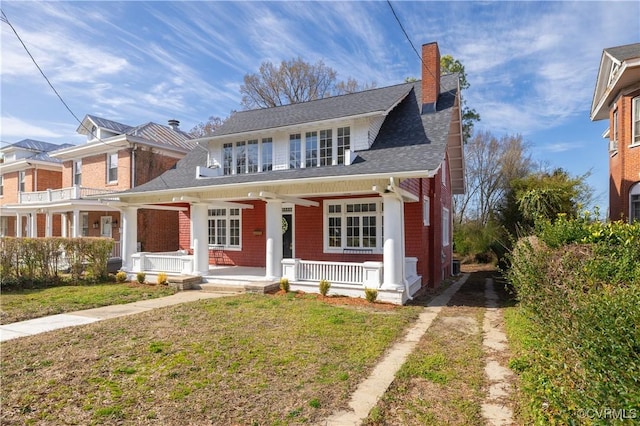 bungalow-style home featuring a porch, a chimney, a front lawn, and a shingled roof