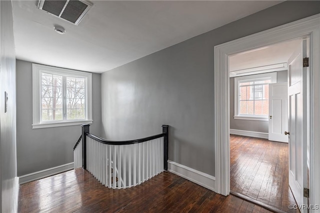 hall with visible vents, an upstairs landing, baseboards, and hardwood / wood-style flooring