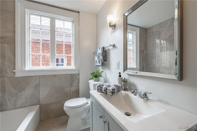 full bathroom with a bathing tub, toilet, a healthy amount of sunlight, and vanity