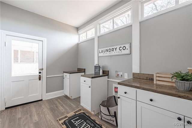 laundry room featuring hookup for a washing machine, cabinet space, baseboards, and light wood finished floors