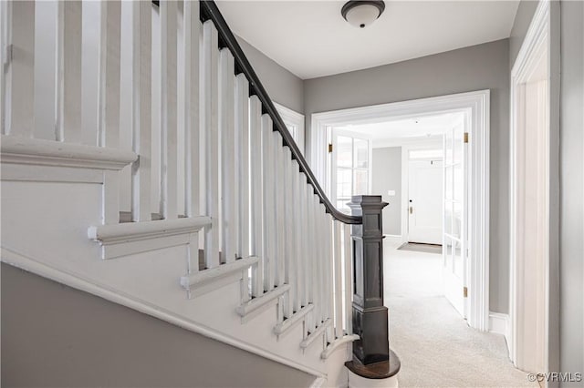 stairway with baseboards and carpet floors