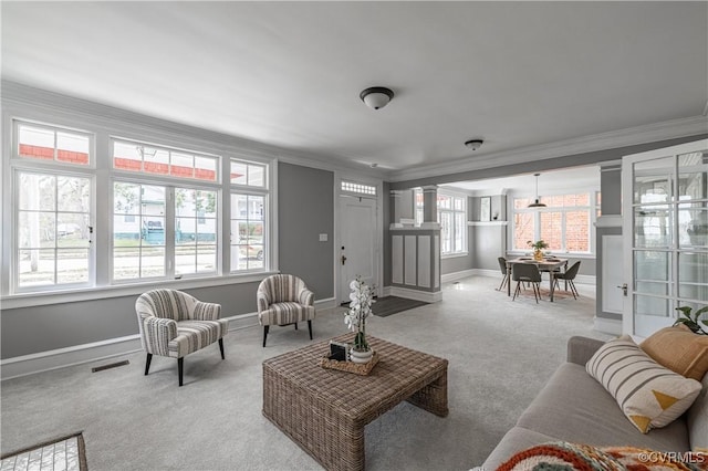 living area with a wealth of natural light, visible vents, carpet, and ornamental molding