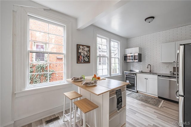 kitchen with a sink, visible vents, light wood finished floors, and stainless steel appliances