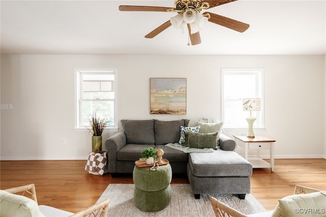 living room featuring a ceiling fan, baseboards, and wood finished floors