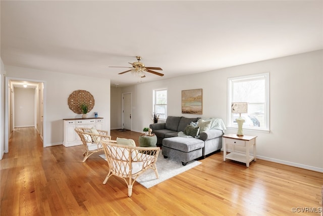 living room featuring light wood-type flooring, baseboards, and ceiling fan