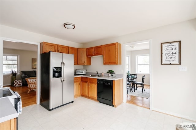 kitchen featuring a healthy amount of sunlight, stainless steel fridge with ice dispenser, a sink, light countertops, and dishwasher