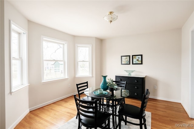 dining room with plenty of natural light, baseboards, and light wood finished floors