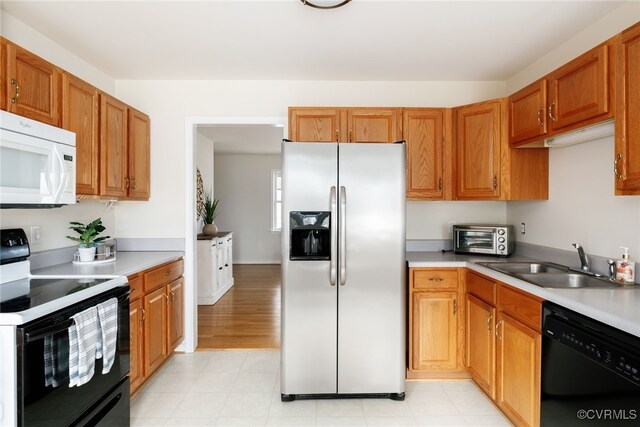 kitchen featuring black appliances, a toaster, light countertops, and a sink