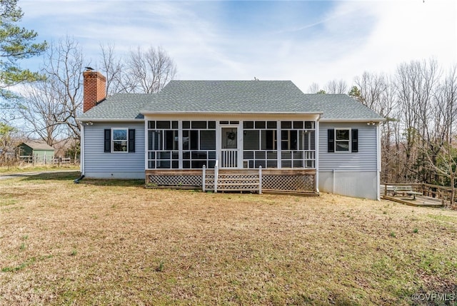 back of property with a yard, roof with shingles, a chimney, and a sunroom