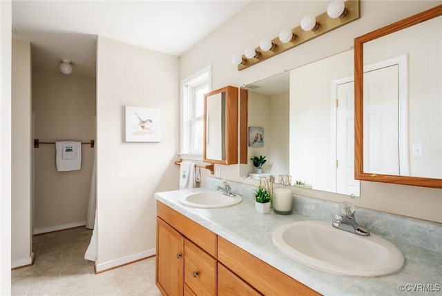 bathroom featuring a sink, baseboards, double vanity, and tile patterned floors