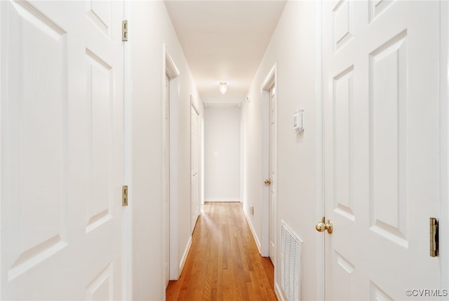 corridor with visible vents, baseboards, and light wood finished floors