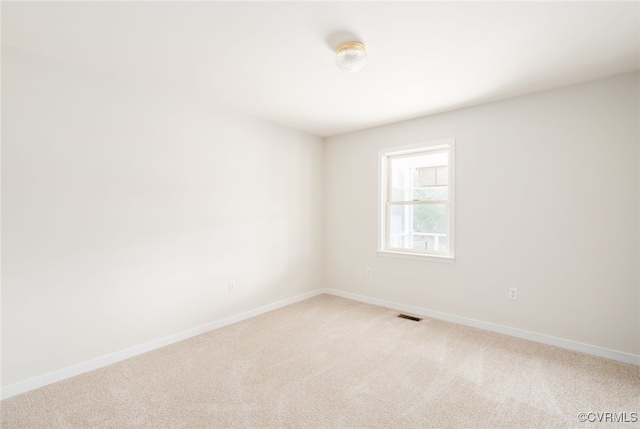 spare room with visible vents, light colored carpet, and baseboards