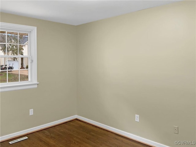 spare room with visible vents, baseboards, and dark wood-style flooring