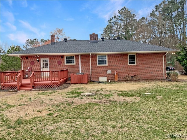 rear view of property with brick siding, a shingled roof, a wooden deck, a lawn, and crawl space