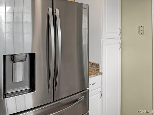 room details featuring white cabinetry, light stone countertops, and stainless steel fridge