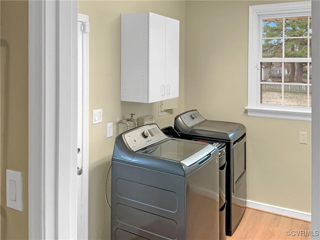 laundry room featuring cabinet space, separate washer and dryer, light wood-type flooring, and baseboards