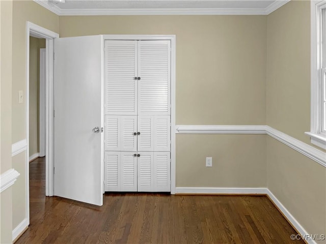 unfurnished bedroom with baseboards, a closet, dark wood-style flooring, and ornamental molding