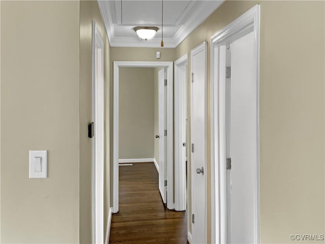 hallway featuring attic access, crown molding, dark wood-style flooring, and baseboards