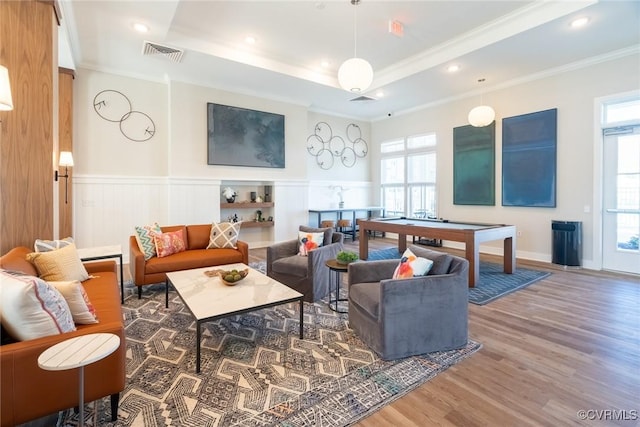 rec room with visible vents, wood finished floors, a tray ceiling, and a wainscoted wall