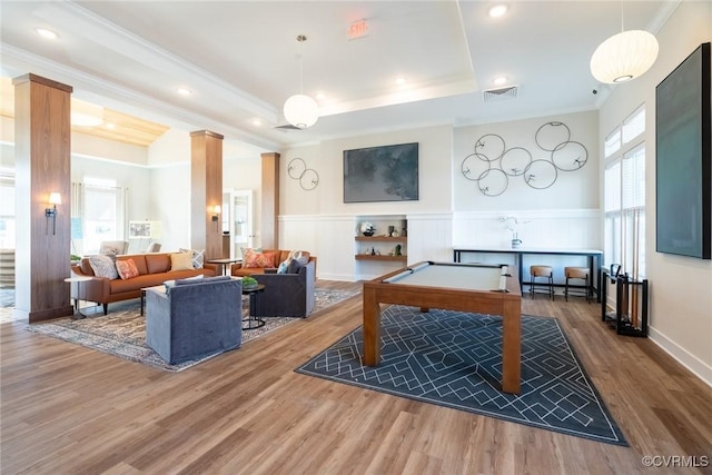 game room featuring wood finished floors, a wainscoted wall, visible vents, ornamental molding, and a raised ceiling