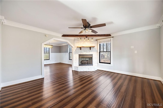 unfurnished living room featuring ornamental molding, dark wood-style floors, a fireplace, baseboards, and ceiling fan