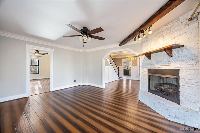 unfurnished living room featuring baseboards, stairway, beamed ceiling, a fireplace, and wood finished floors