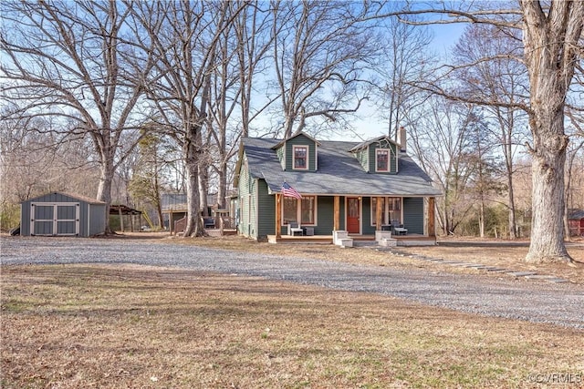 view of front of property with a front lawn, covered porch, a chimney, an outbuilding, and a storage unit