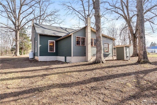 exterior space with a storage unit, an outbuilding, and a chimney