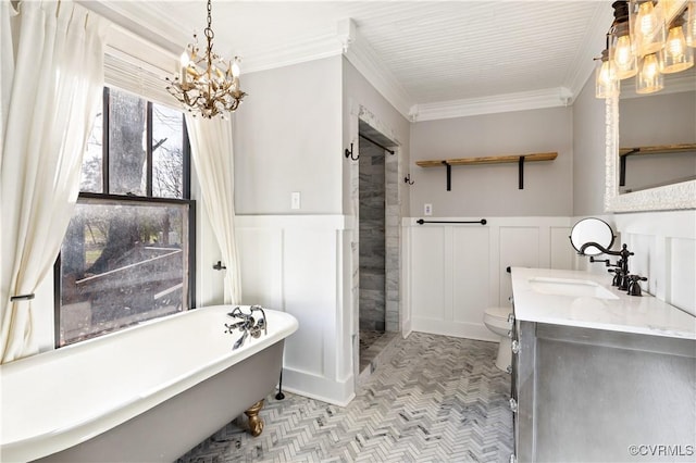 full bath with a soaking tub, wainscoting, toilet, and crown molding