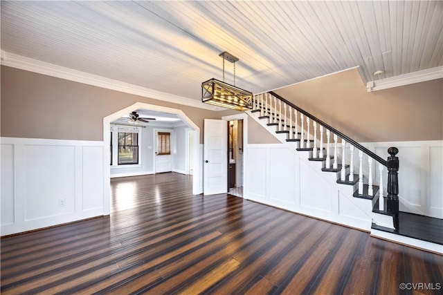 foyer entrance with stairs, ornamental molding, arched walkways, a decorative wall, and dark wood-style flooring