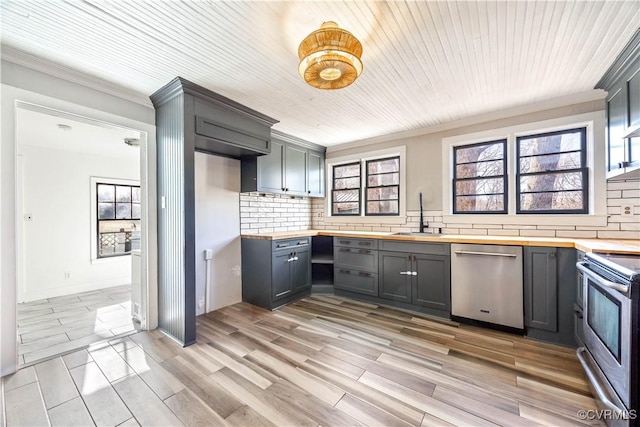 kitchen with a sink, stainless steel appliances, backsplash, and butcher block countertops