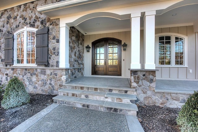 entrance to property with stone siding, board and batten siding, and french doors