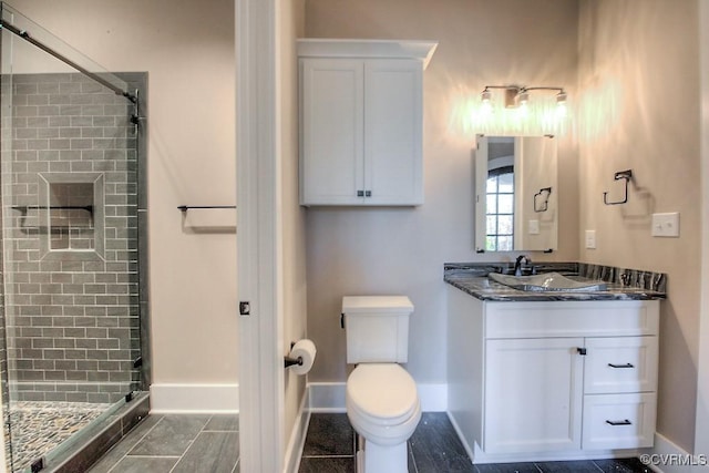 full bathroom with vanity, toilet, baseboards, and a stall shower