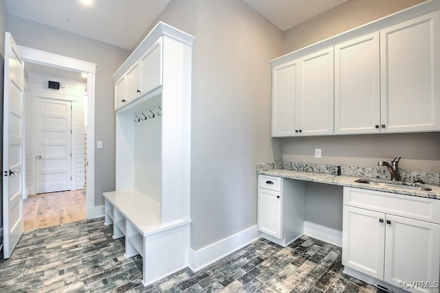 mudroom with dark wood finished floors, baseboards, and a sink