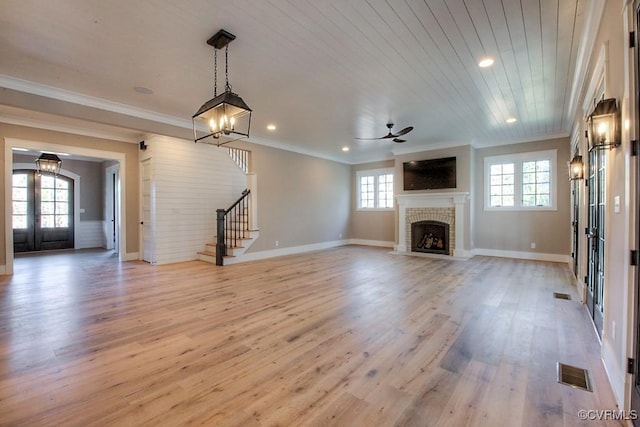 unfurnished living room featuring visible vents, plenty of natural light, a brick fireplace, and stairs