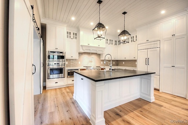 kitchen featuring a sink, a barn door, appliances with stainless steel finishes, and white cabinetry