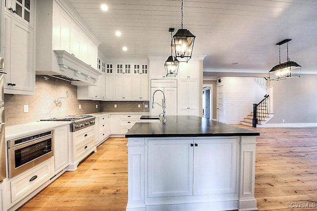 kitchen featuring stainless steel gas cooktop, white cabinets, oven, and light wood-style floors