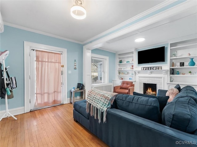 living area with a brick fireplace, baseboards, light wood-type flooring, and ornamental molding