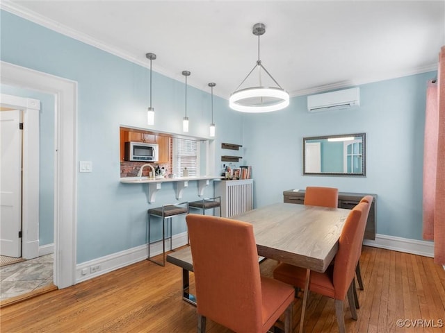 dining room with ornamental molding, baseboards, light wood finished floors, and a wall mounted AC