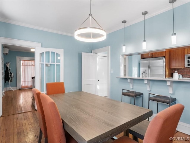 dining space with crown molding, baseboards, and wood-type flooring